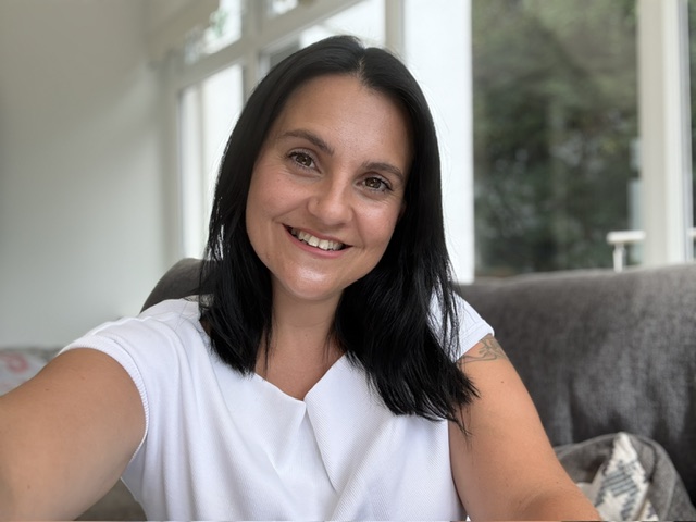 Steph smiling at home in a white top